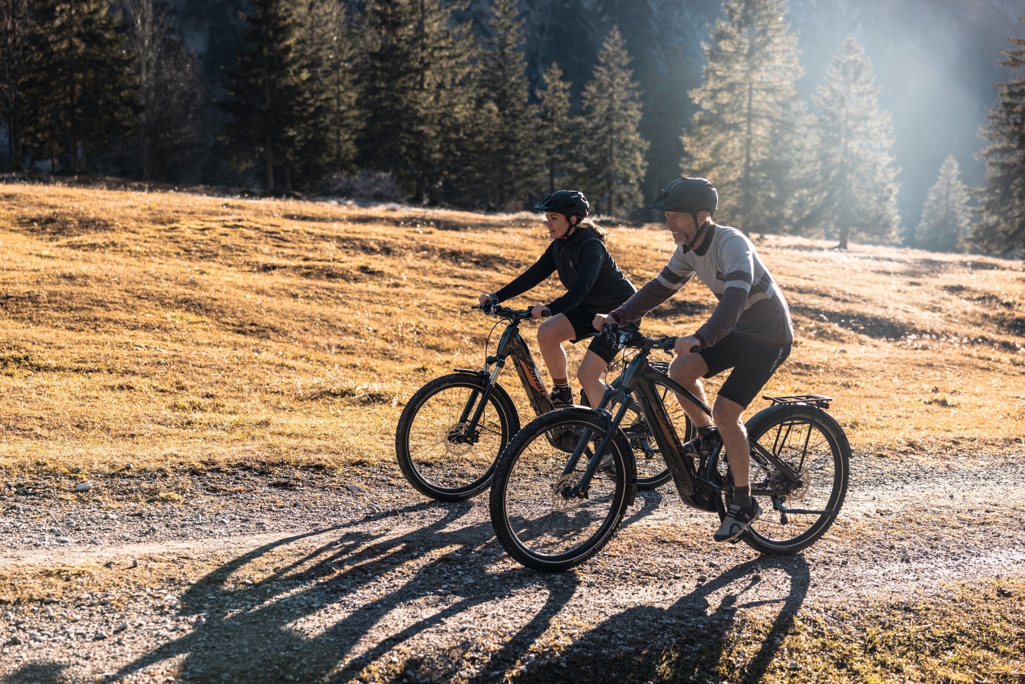 Zwei Personen fahren auf Trekking e-Bikes von Corratec durch herbstliche Landschaft.