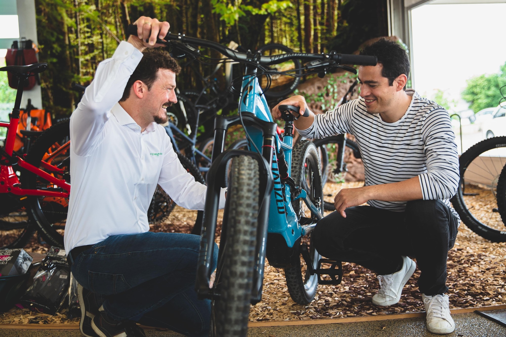 zwei Personen in einem Fahrradladen, die sich mit der ergonomischen Einstellung eines E-Bikes beschäftigen.