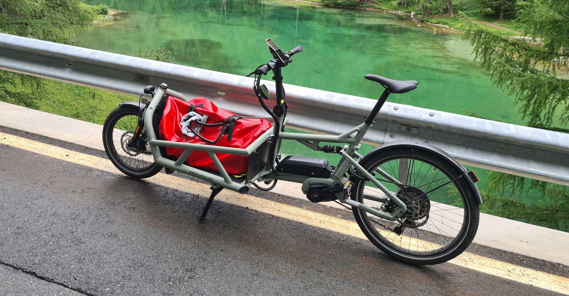 Riese & Müller Lasten e-Bike steht an einem Fluss und macht Pause.