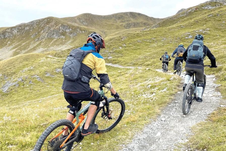 Mountainbiker auf schmalem Pfad in alpiner Landschaft