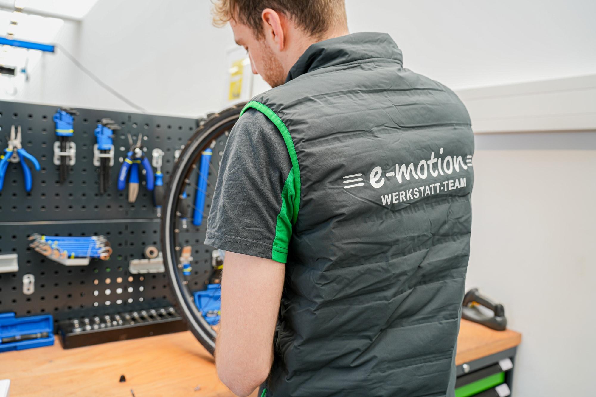 Ein Mitarbeiter des e-motion Werkstatt-Teams wartet ein Fahrrad in einer gut ausgestatteten Werkstatt mit professio
