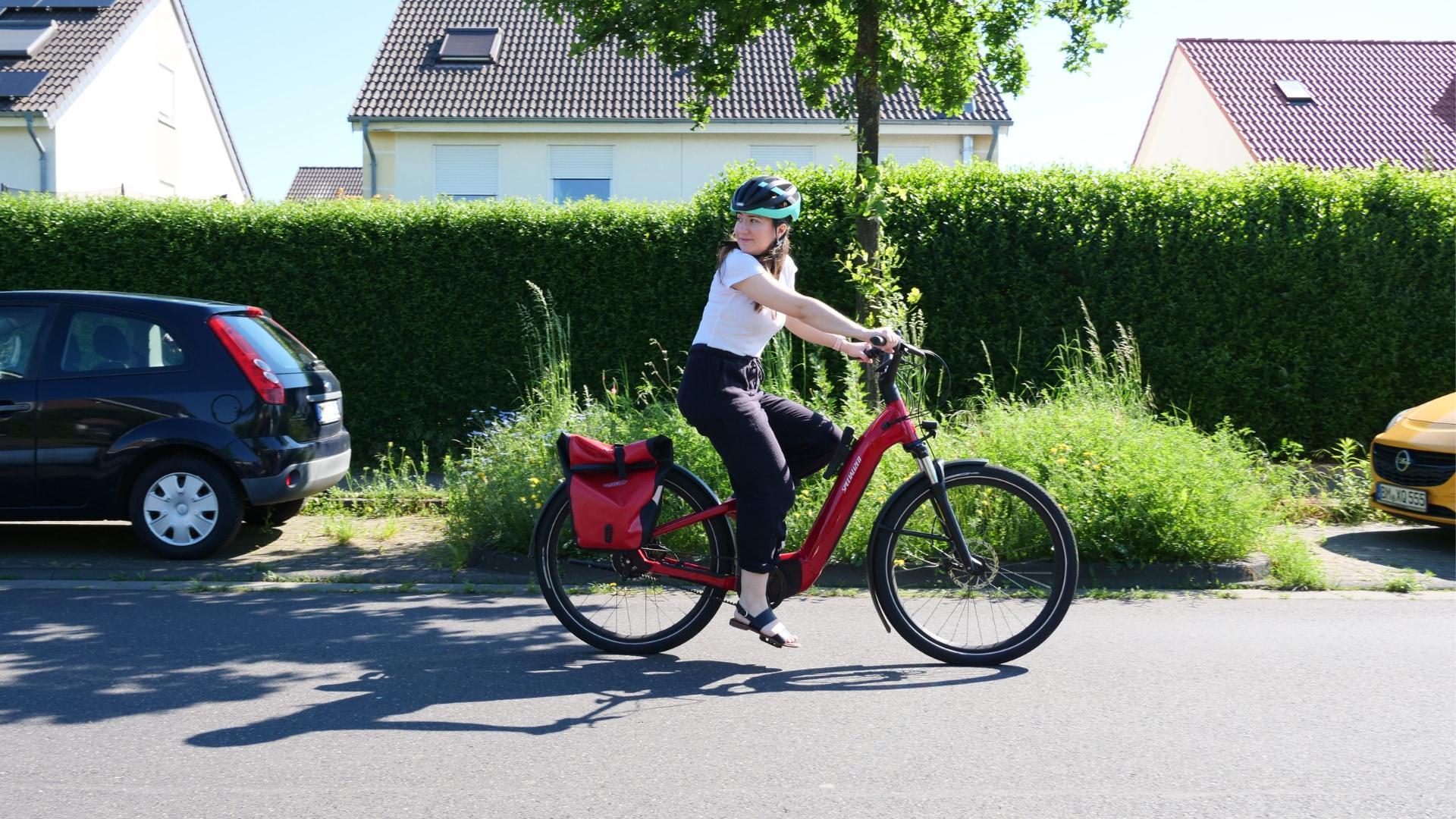 Fahrerin auf einem eleganten roten E-Bike, entspannt durch die Straße gleitend, ideal für urbane Mobilität und umwe