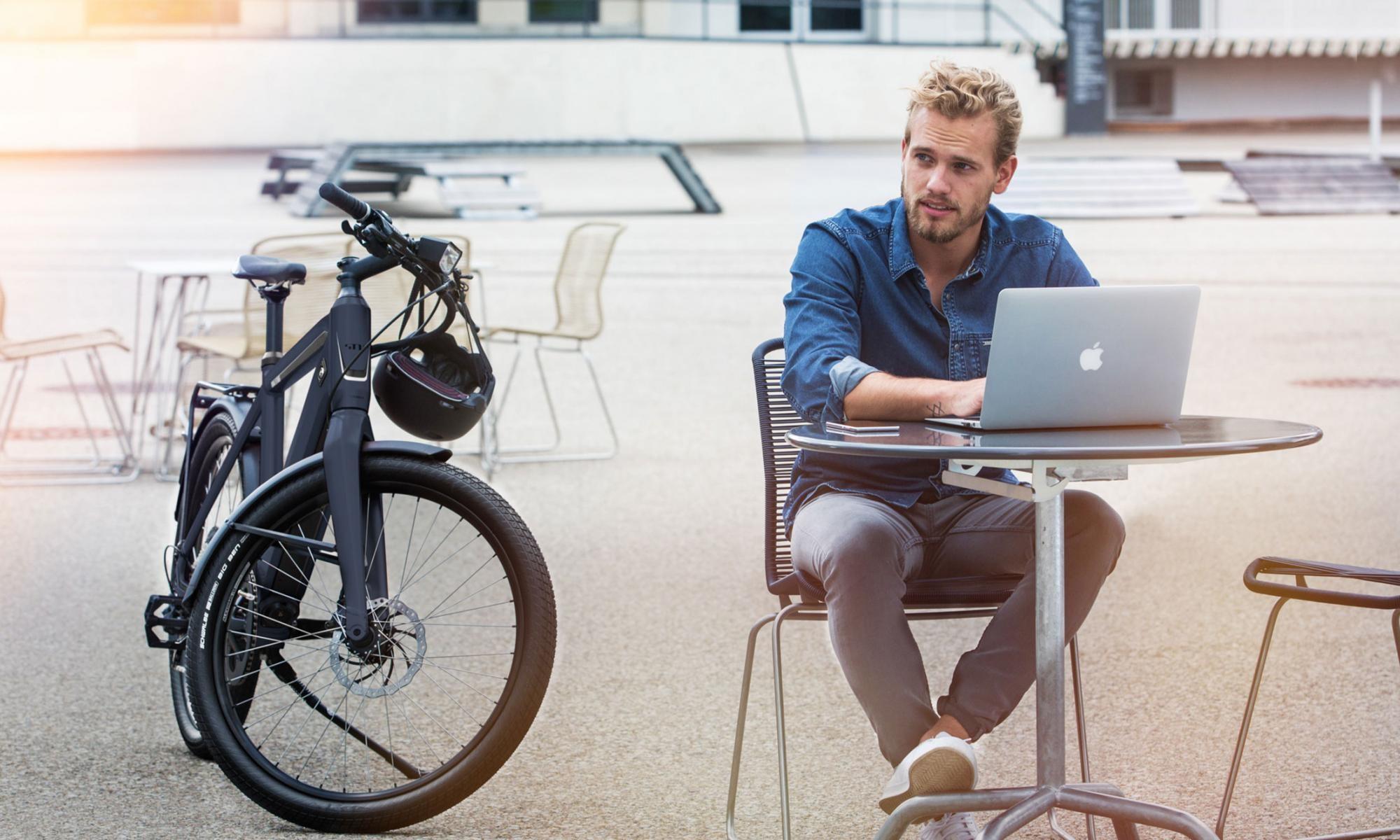 Das Bild zeigt ein Stromer ST1X E-Bike, das elegant neben einem Tisch platziert ist.