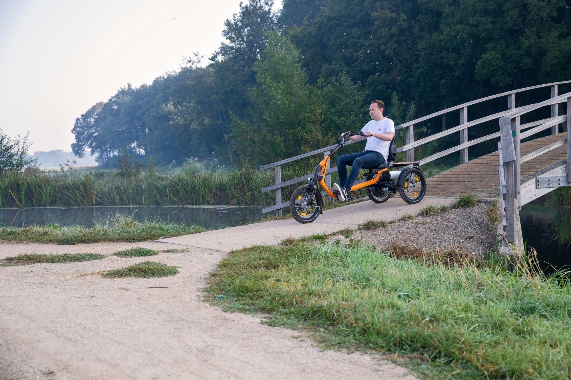 Ein Mann fährt mit dem Easy Rider 3 vanRaam Dreirad über eine Brücke aus Holz
