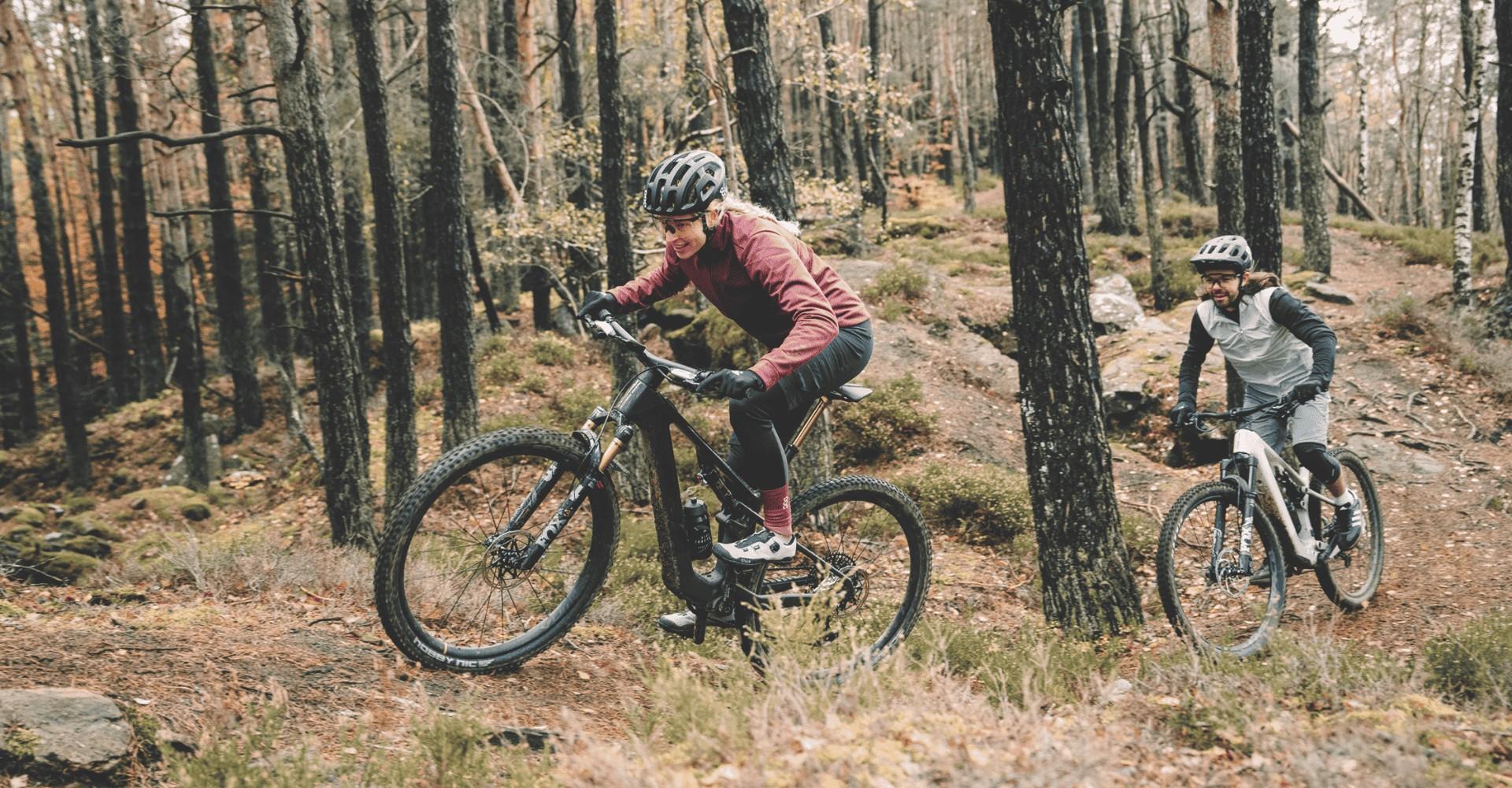 Zwei Personen fahren mit ihren Focus VAM2 SL Light e-Mountainbikes durch den Wald