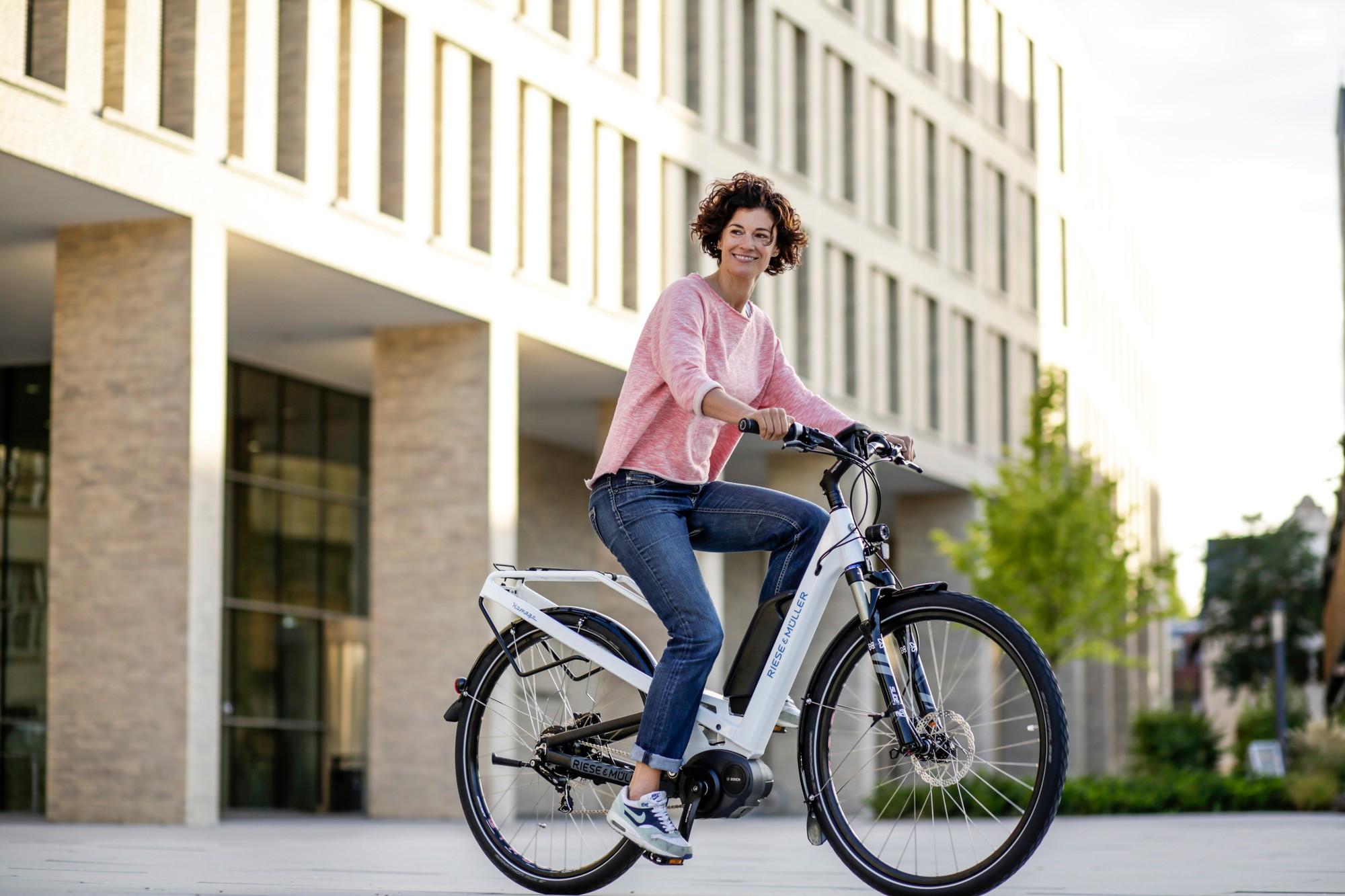 Das Bild zeigt eine Frau, die auf einem Riese und Müller Homage E-Bike sitzt, einem Modell aus dem Jahr 2017.