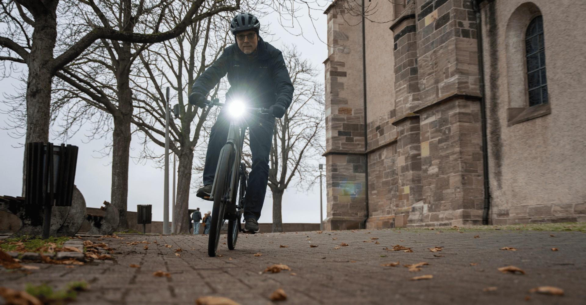 Das Bild zeigt einen Radfahrer, der auf einem Riese & Müller UBN Five E-Bike fährt. Das E-Bike ist ausgestattet mit