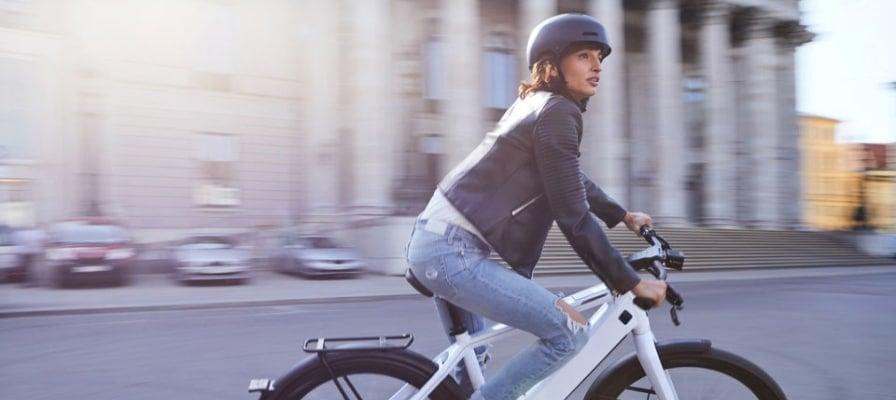 Frau auf weißem Speed-Pedelec in der Stadt mit Helm