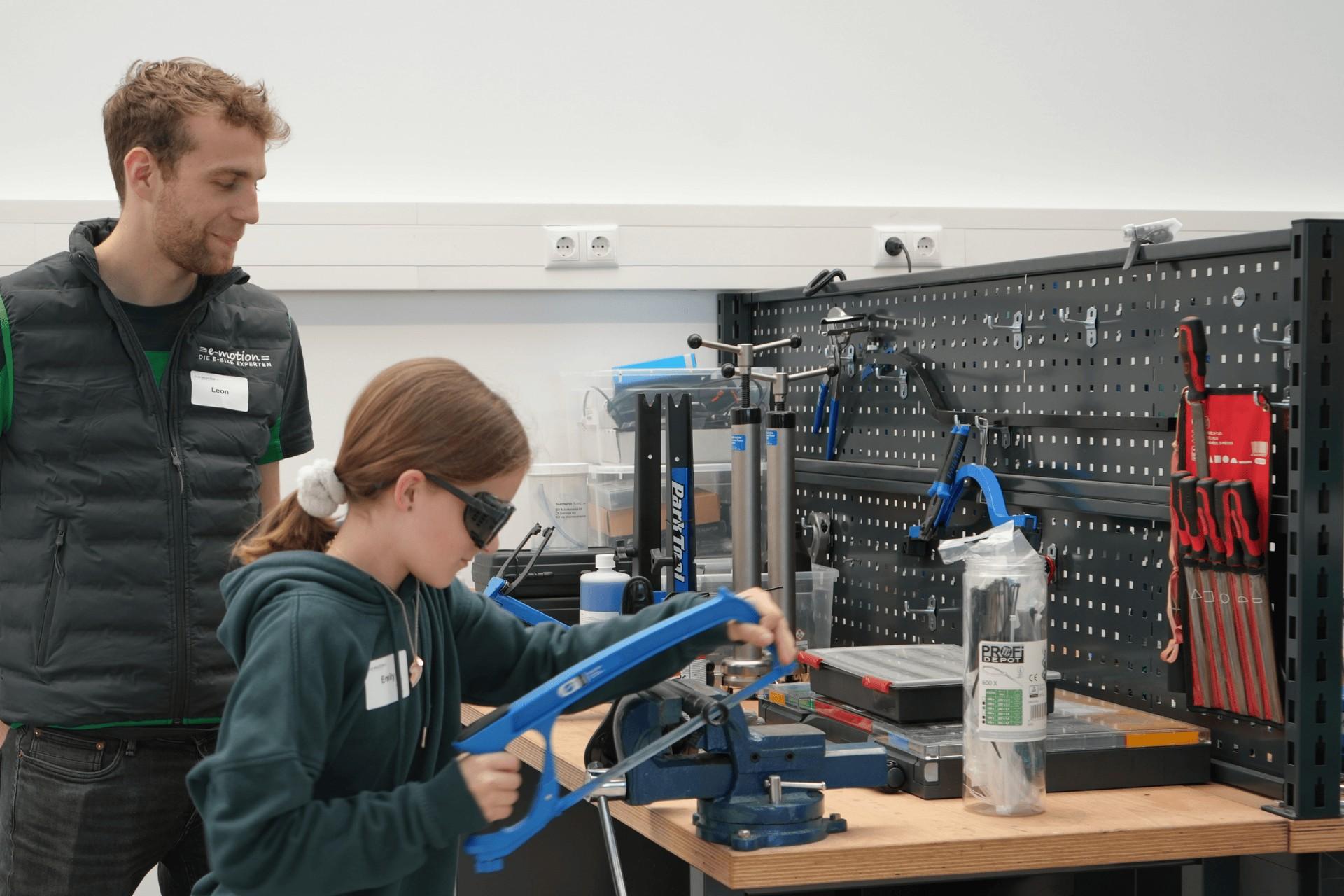 Teilnehmerin des Girls' Day und Werkstattmitarbeiter an der Werkbank