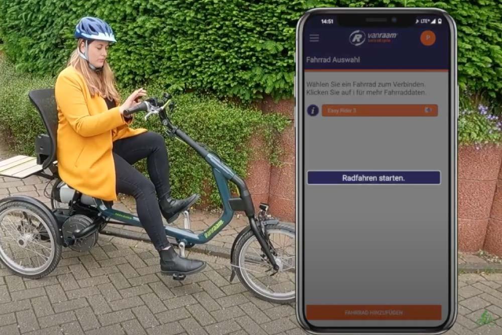 Eine Frau sitzt auf einem vanRaam Dreirad und nutzt die App
