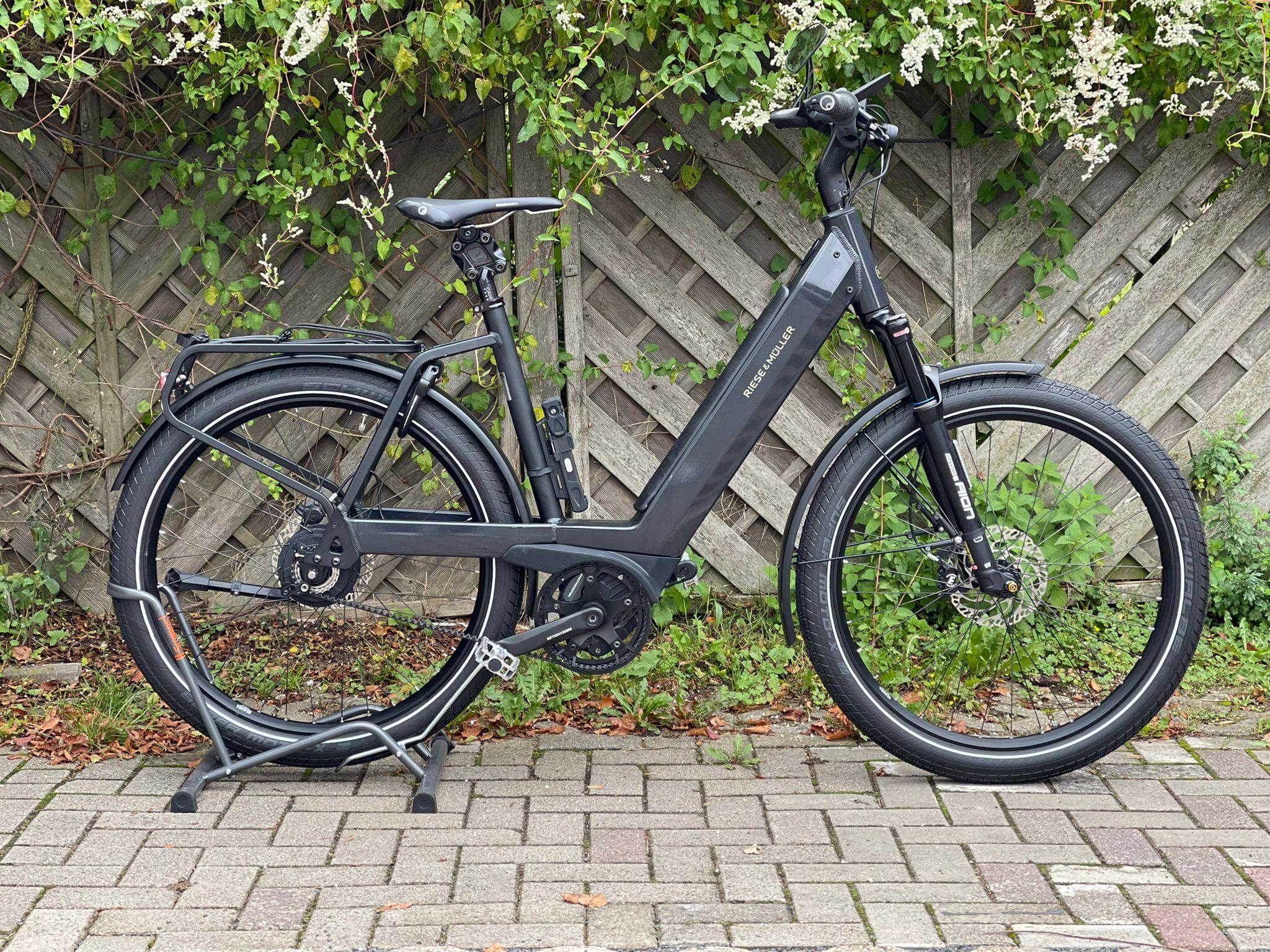 Das neue Riese & Müller Nevo3GT vario steht vor einem Gartenzaun.