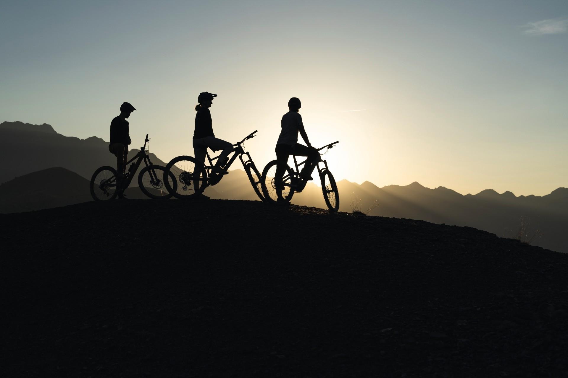 Das Bild zeigt drei Menschen mit dem Specialized Kenevo SL beim Sonnenuntergang