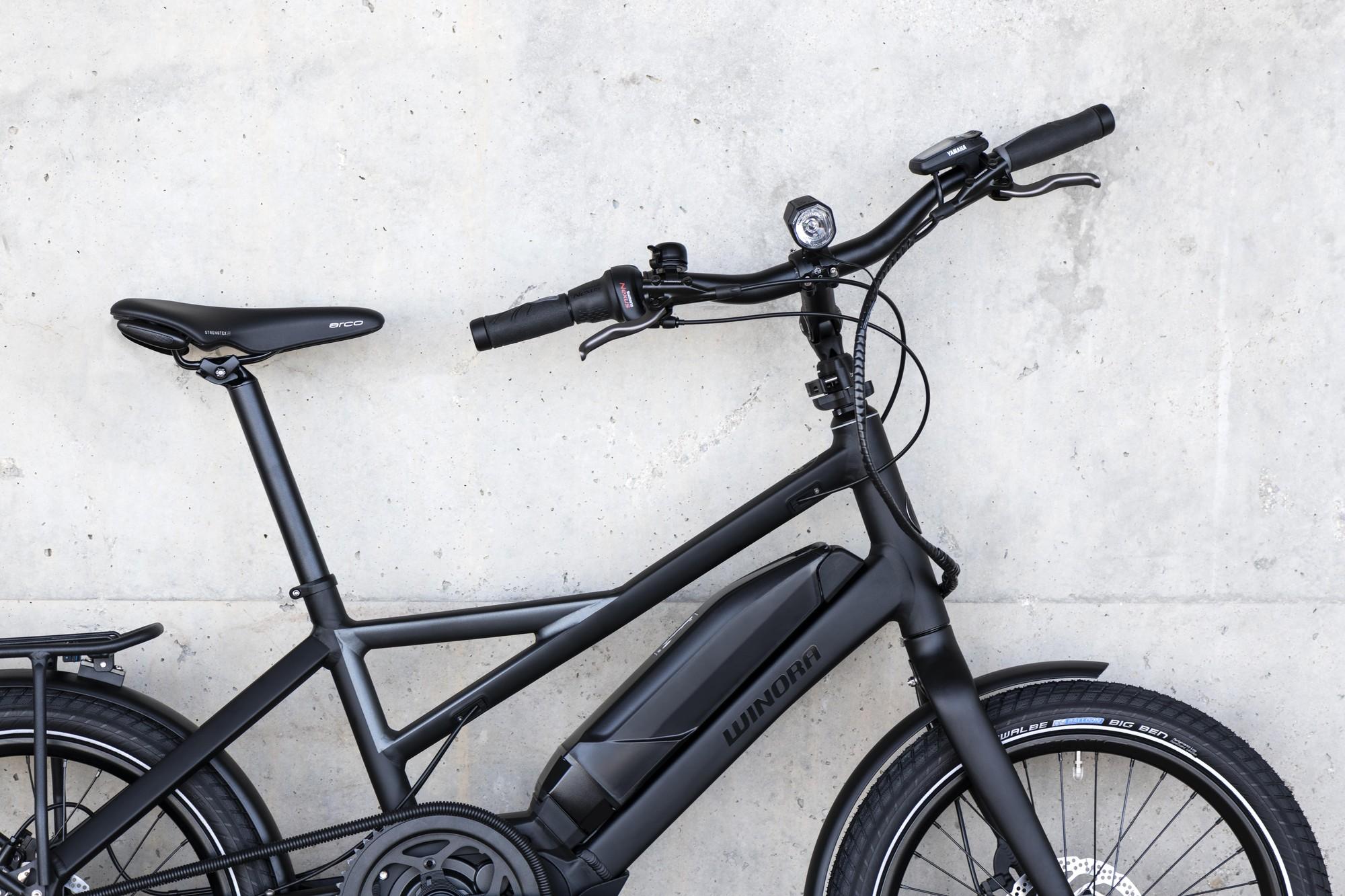 Das Bild zeigt ein Winora Urban Radius Tour E-Bike in einem minimalistischen, mattschwarzen Finish. Der Rahmen ist