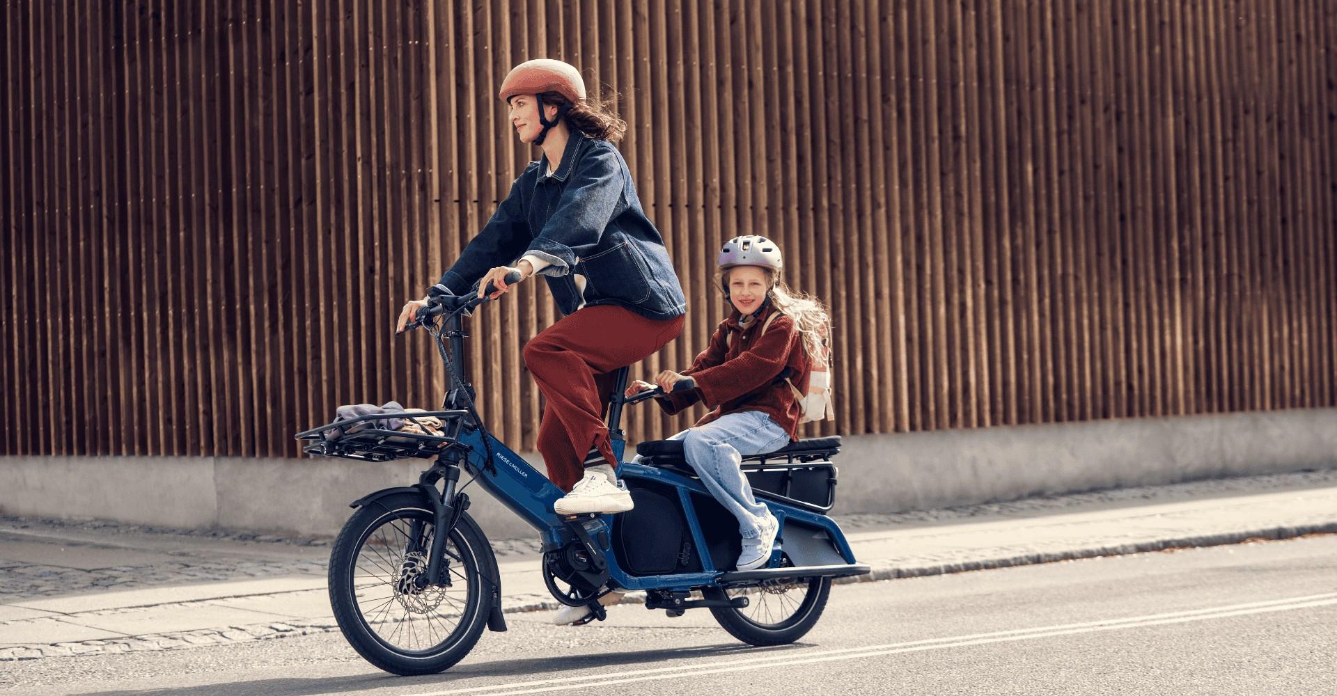 Eine Frau fährt mit dem Riese und Müller Multitinker, auf dem Gepäckträger sitzt ein Mädchen