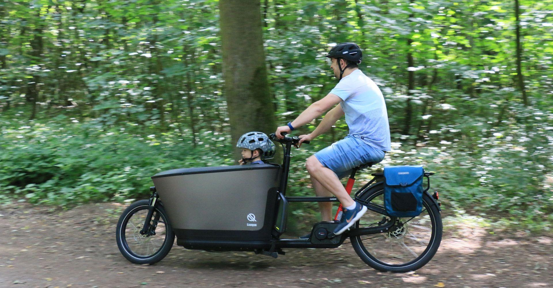 Marcus sitzt auf dem Carqon Classic, in der Transport seine Kinder