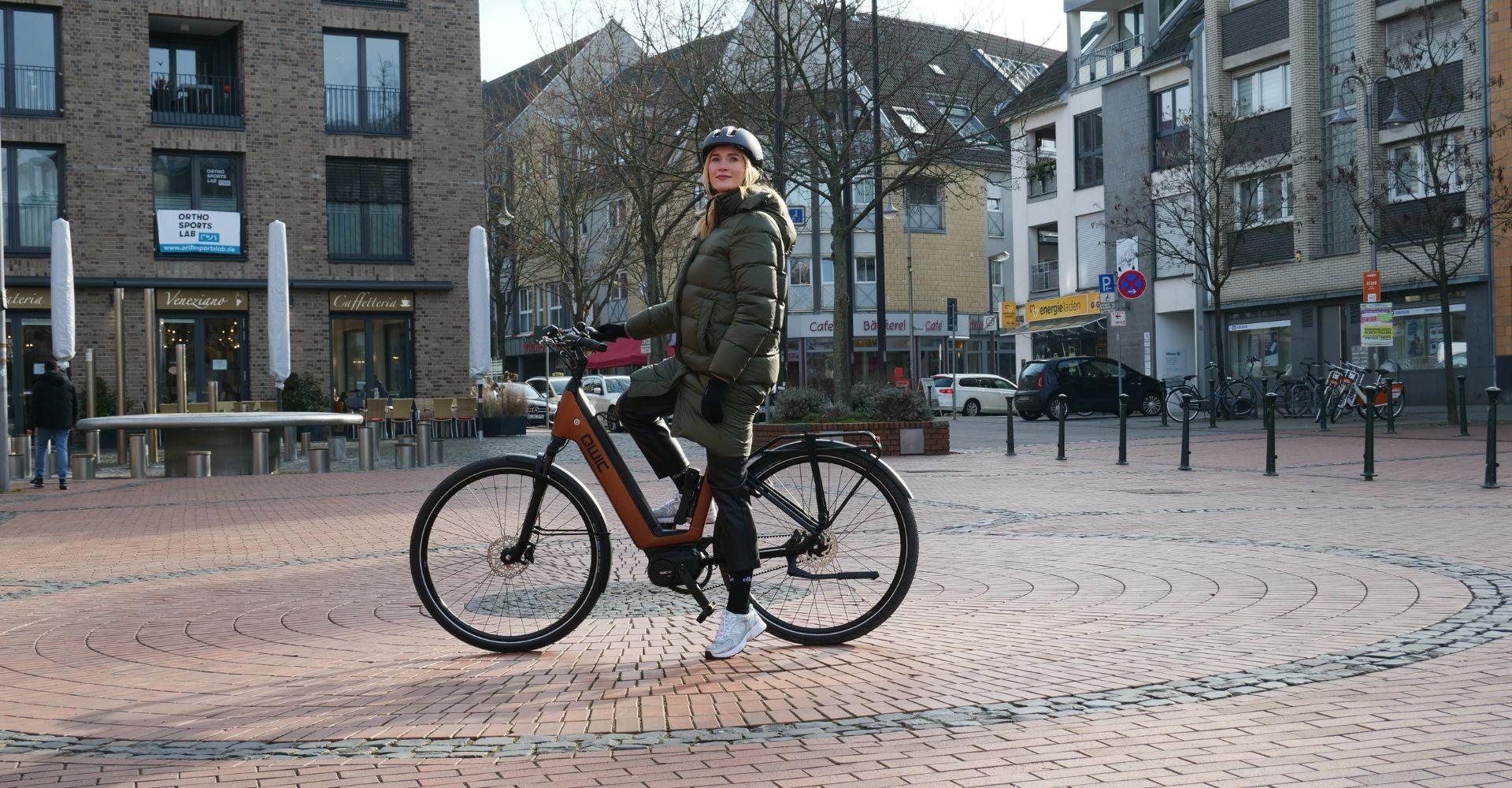 Laura fährt mit dem QWIC Mira Tour e-Bike durch die Stadt