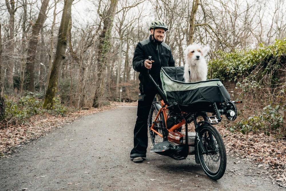 Ein Mann der mit seinem Pino von Hase Bikes seinen Hund transportiert