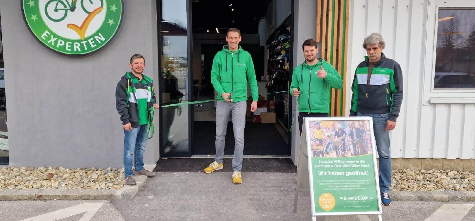 Eröffnung eines E-Bike-Shops mit vier Personen und Werbeschild