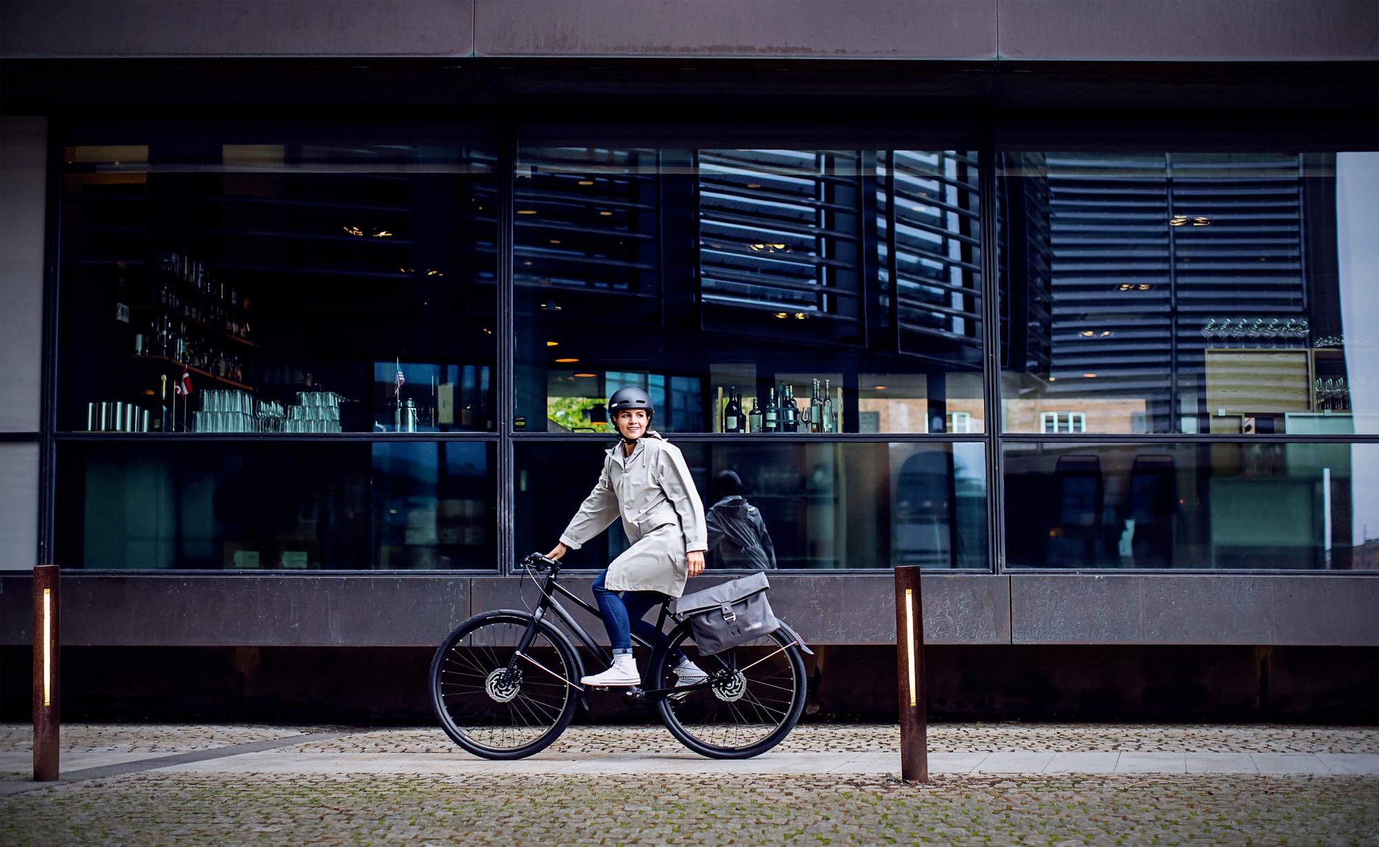 Eine Person fährt ein modernes E-Bike vor einem Stadtgebäude. Perfekt für urbane Mobilität und stilvolle Fortbewegu