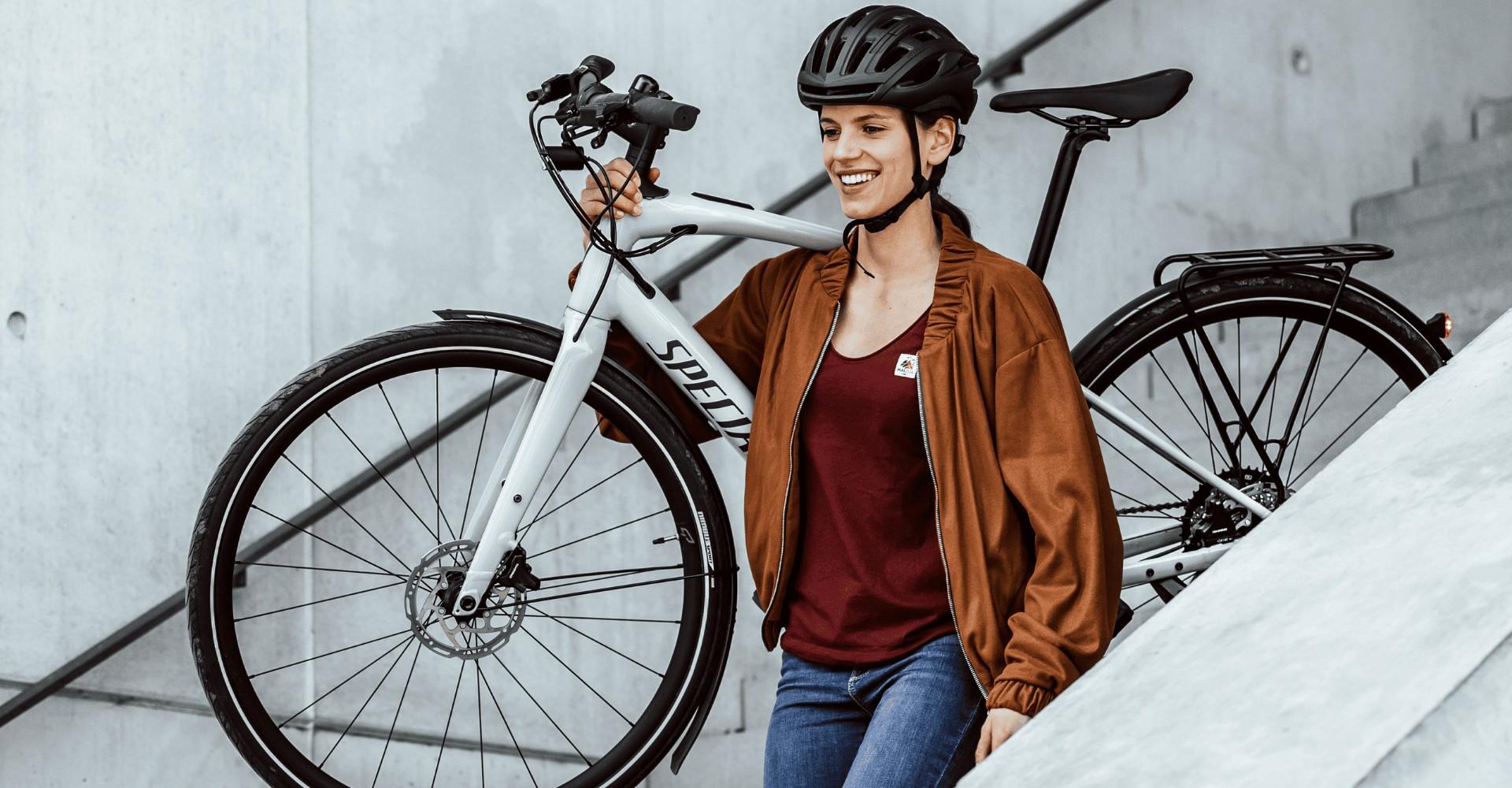 Eine Frau trägt das e-Bike Specialized Vado SL die Treppe runter