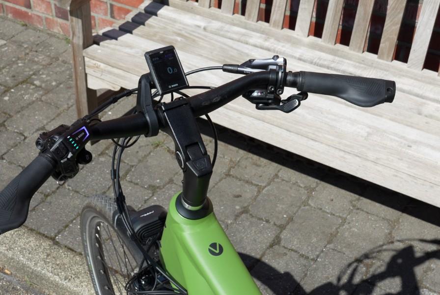Das Bild zeigt den Lenker eines Velo de Ville AEB 990 E-Bikes, der in einem urbanen Umfeld abgebildet ist.