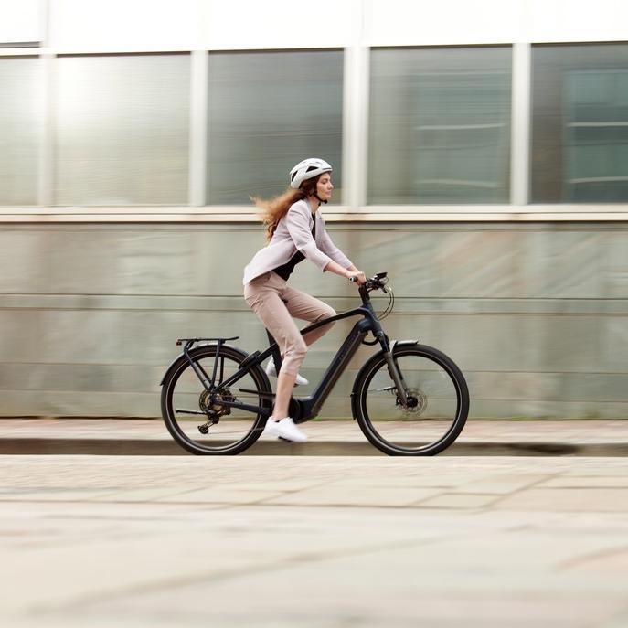 Eine Frau fährt mit einem Kalkhoff e-Bike durch eine urbane Umgebung
