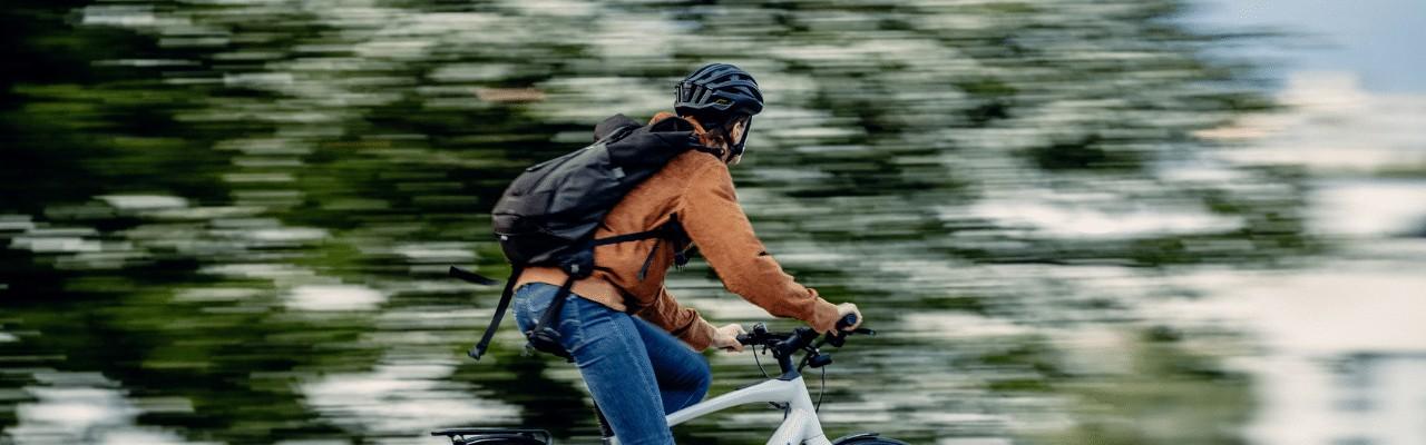 Eine Person fährt schnell auf einem e-Bike, die Bäume im Hintergrund verschwimmen.