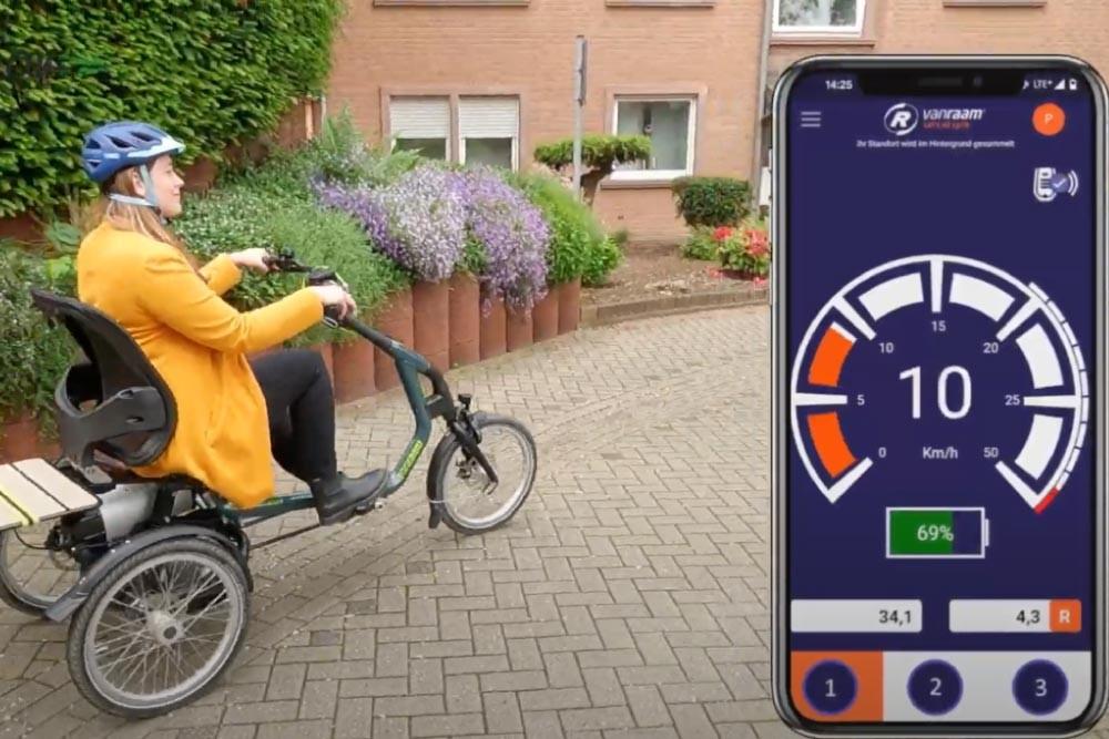 Eine Frau sitzt auf dem Dreirad, außerdem zu sehen die vanRaam App
