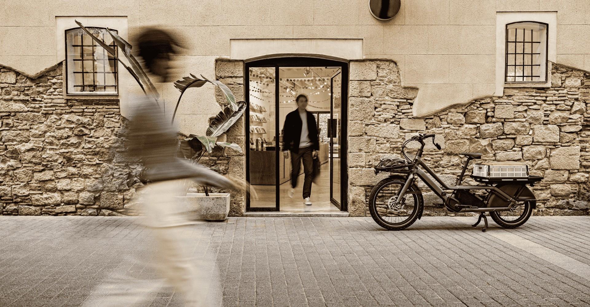 Das Specialized Turbo Porto steht vor einer Steinmauer, aus der Türe kommt ein Mann