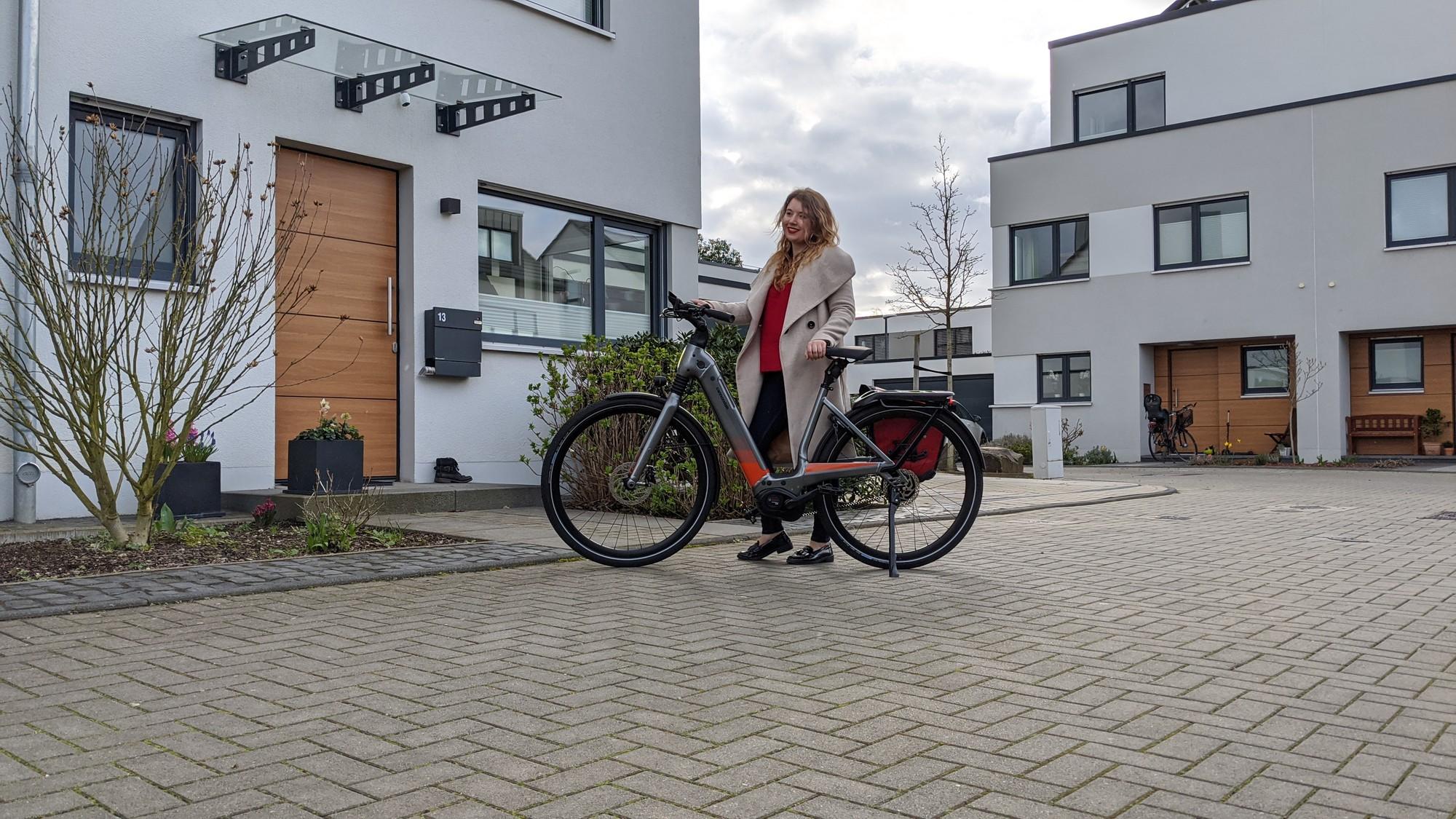 Britt steht vor einem Wohnhaus mit dem e-Bike Mavaro Neo von Cannondale