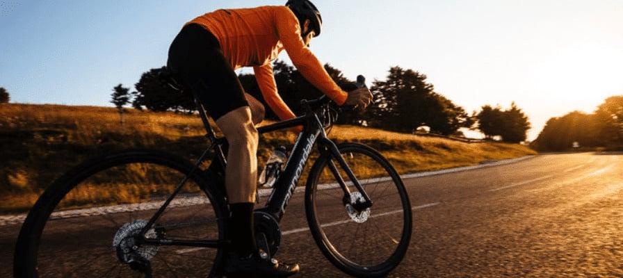 Rennradfahrer bei Sonnenuntergang auf leerer Landstraße