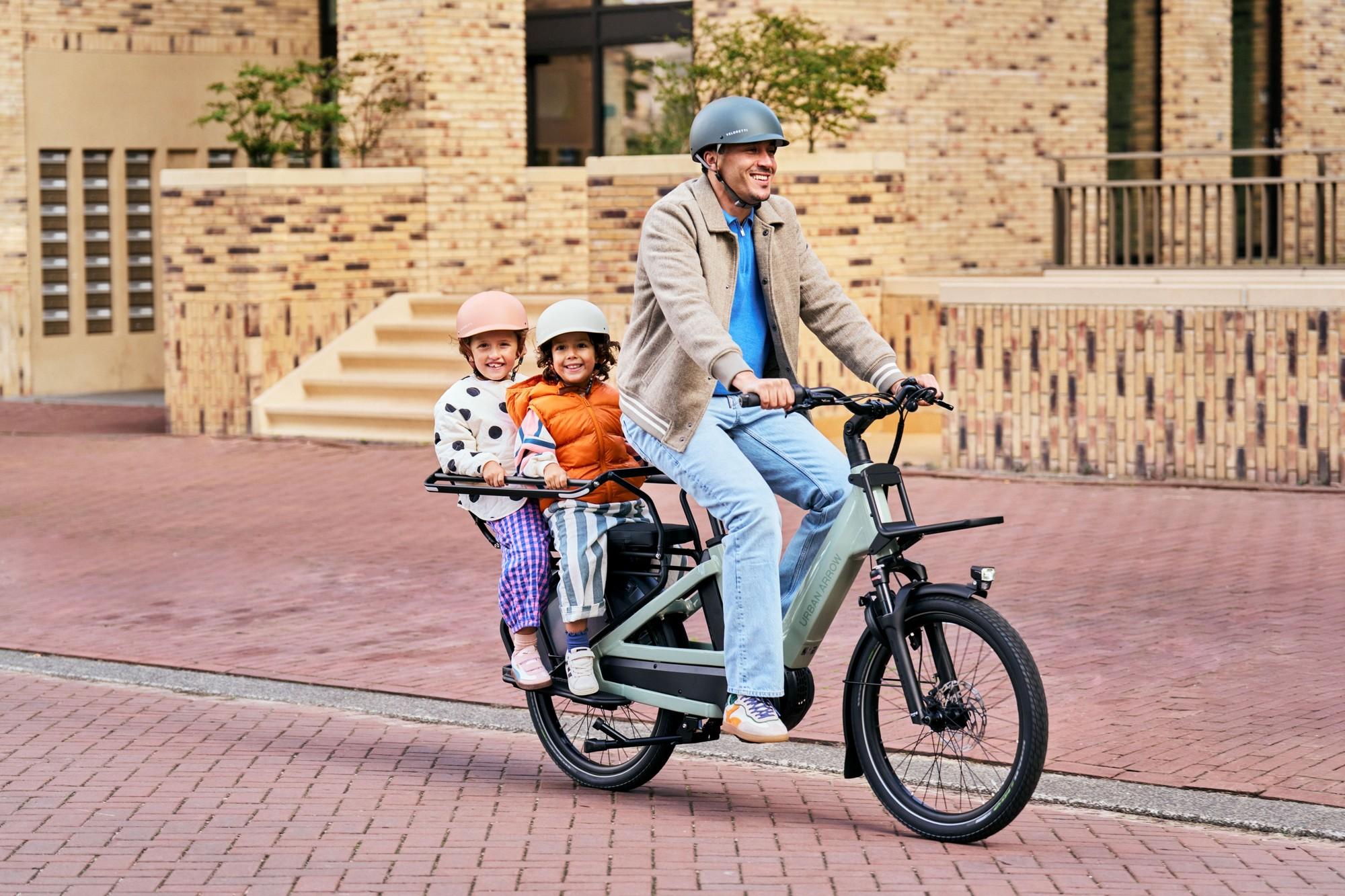 Das Bild zeigt einen Mann mit Kindern auf einem Urban Arrow Breeze