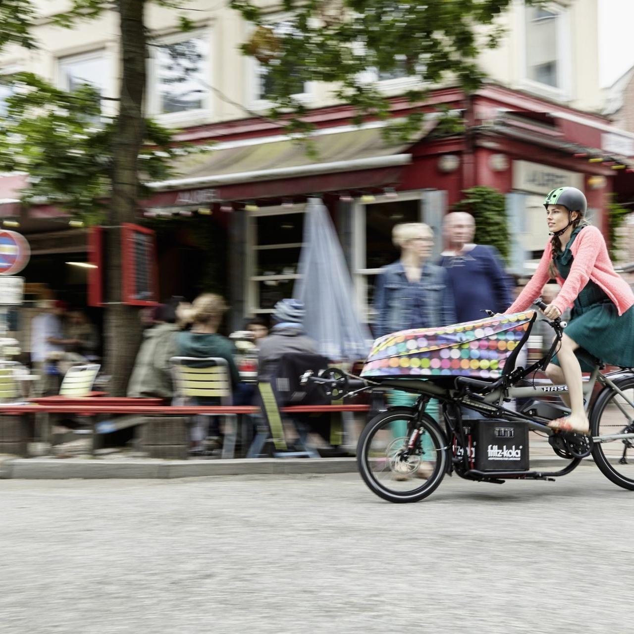Frau fährt mit Hase Bikes Pino Lastenrad durch die Stadt