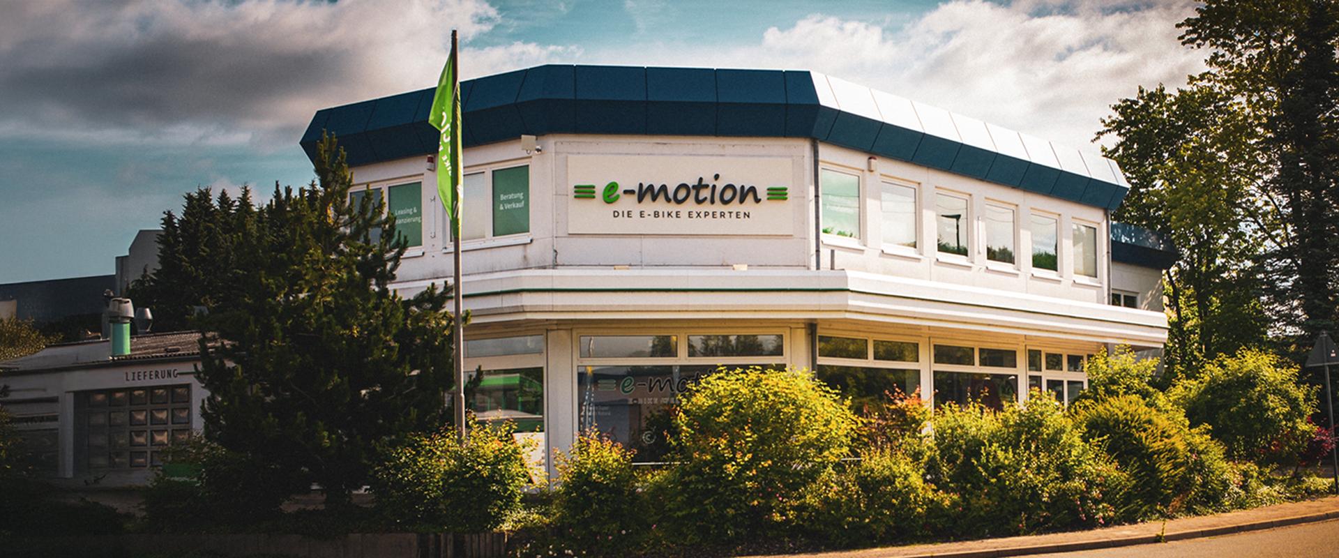 Die Außenfassade der e-motion e-Bike Welt mit einem Fahnenmast und grünen Akzenten