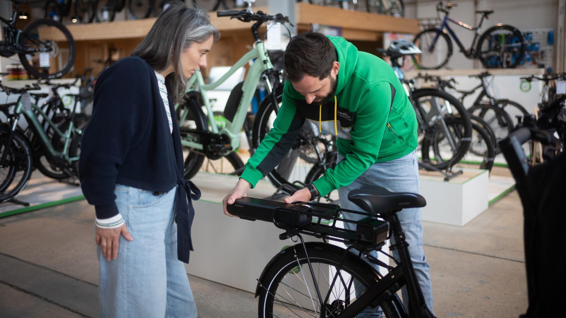e-Bike Berater demonstiert seiner Kundin, wie einfach der Akku vom Bike abgenommen werden kann