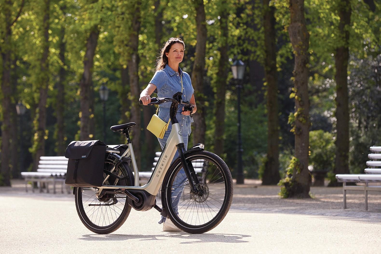 Eine Frau schiebt ein Gazelle e-Bike durch die Stadt