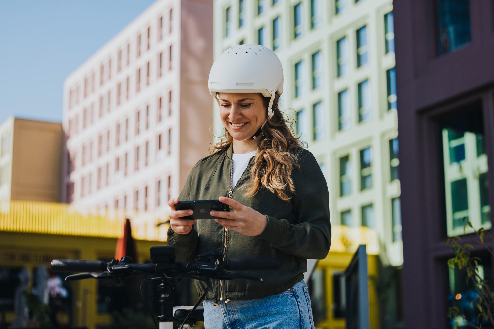 Frau steht mit dem Bosch e-Bike Computer neben ihrem City e-Bike in der Stadt.