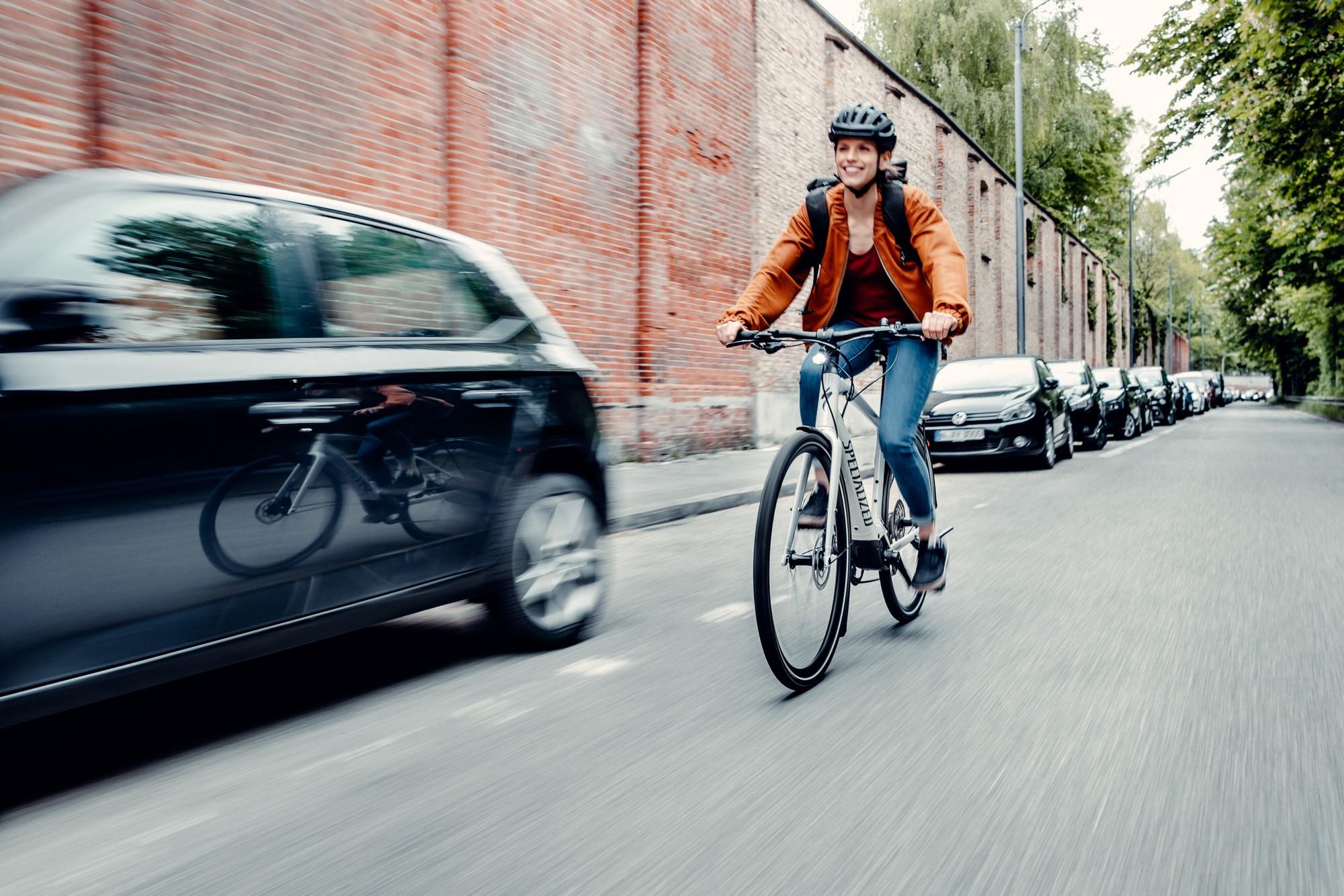 Frau fährt mit ihrem City e-Bike über die Straße mitten in der Stadt.