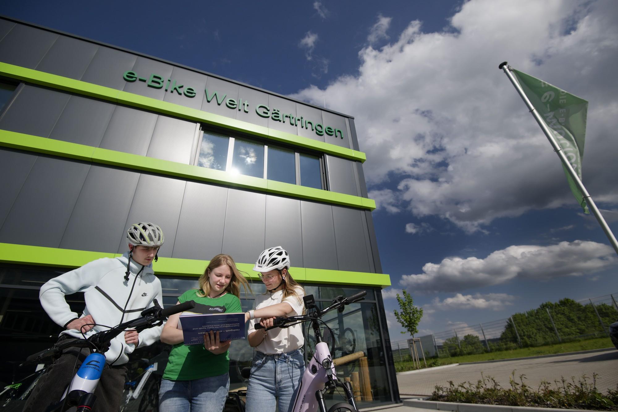 emotion Mitarbeiterin beratet zwei Personen vor dem Gebäude der e-motion e-Bike Welt Gärtringen