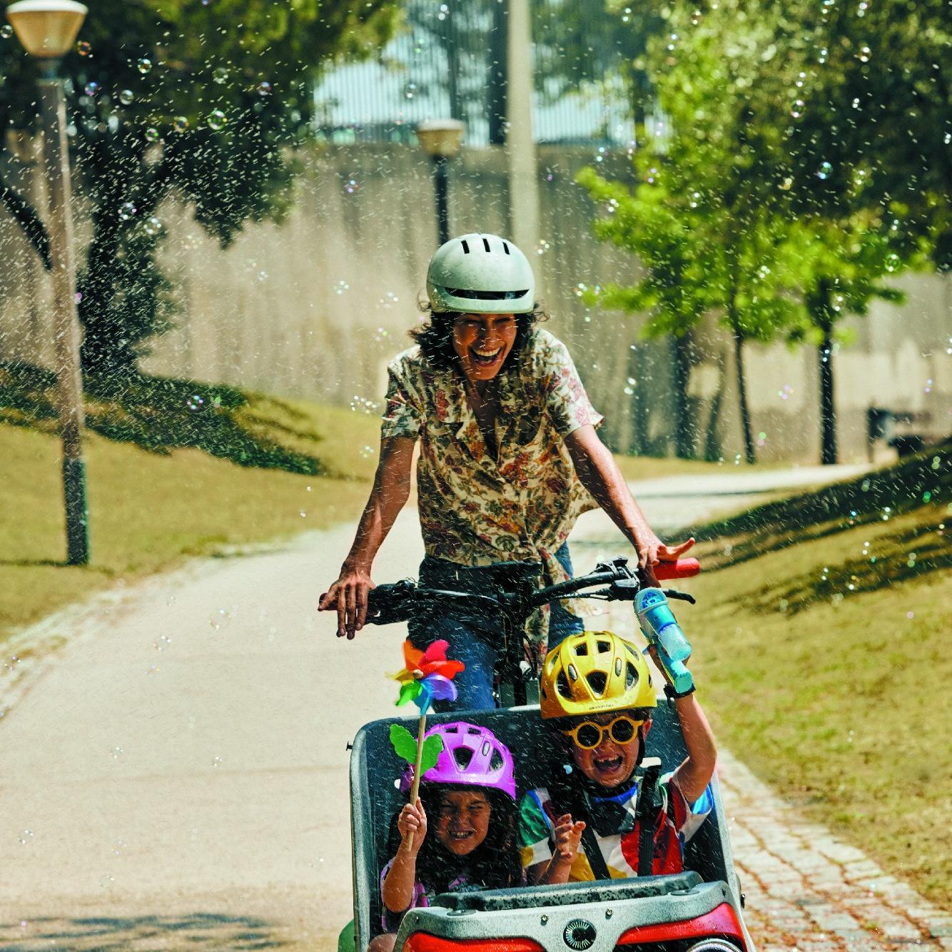 Frau fährt mit Cannondale Wonderwagen und zwei Kindern durch den Park