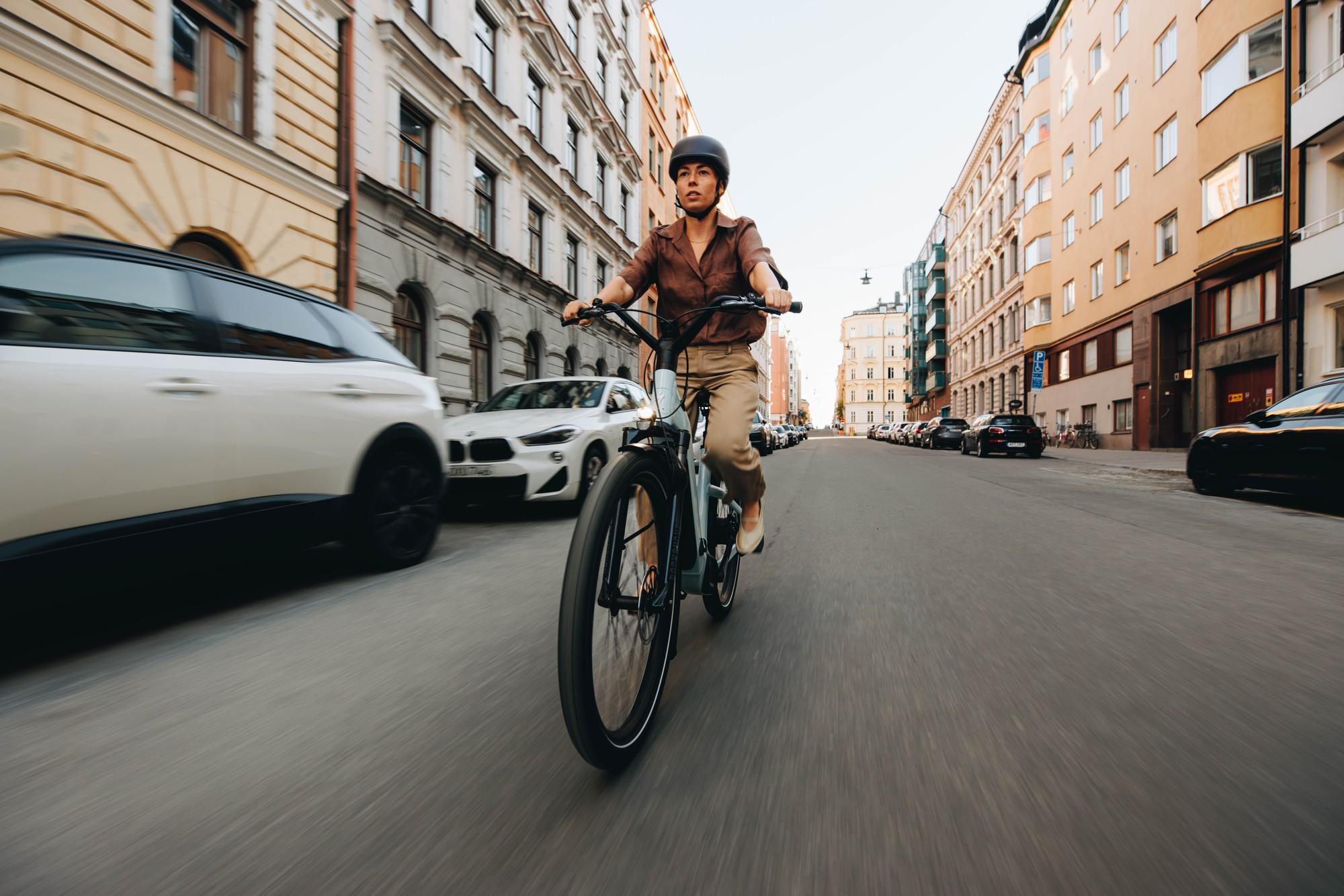 Eine Frau fährt auf dem Specialized Como e-Bike in urbaner Umgebung an Autos vorbei