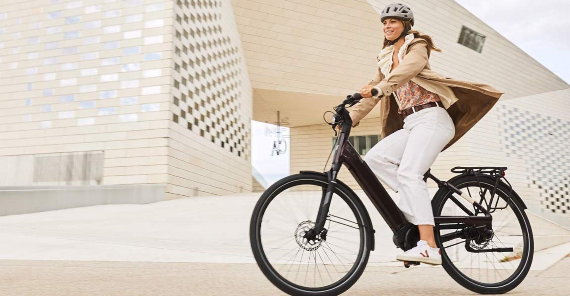 Das Bild zeigt eine Frau, die auf einem Liv Allure E+ 2022 City e-Bike fährt, das für den urbanen Einsatz konzipier