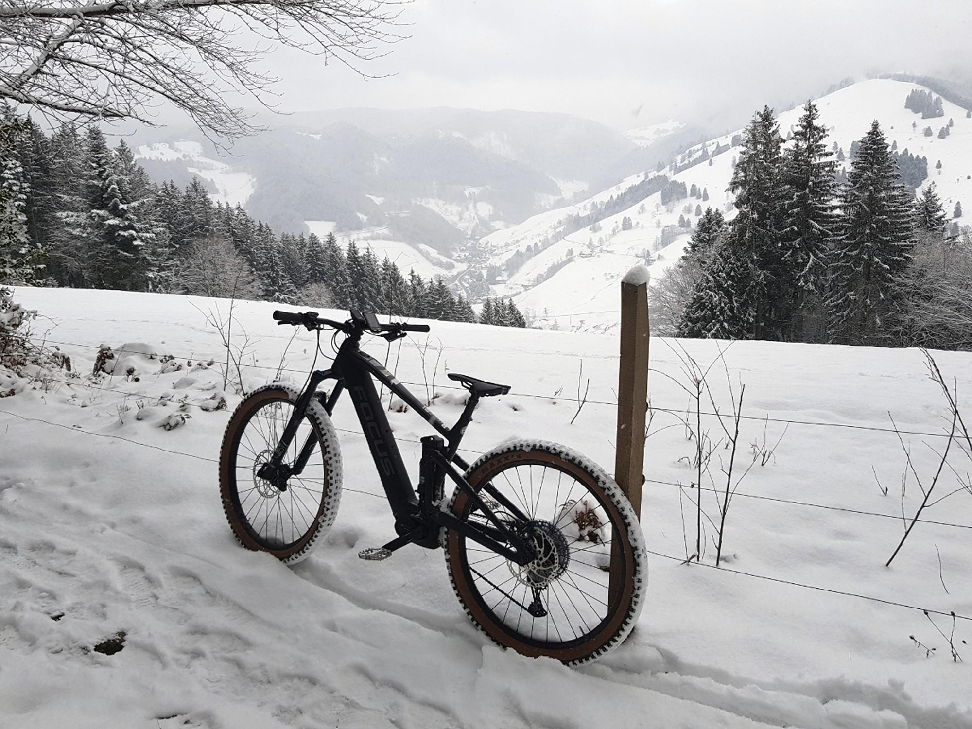 Ein e-Mountainbike steht in den Bergen vor einer verschneiten Landschaft.