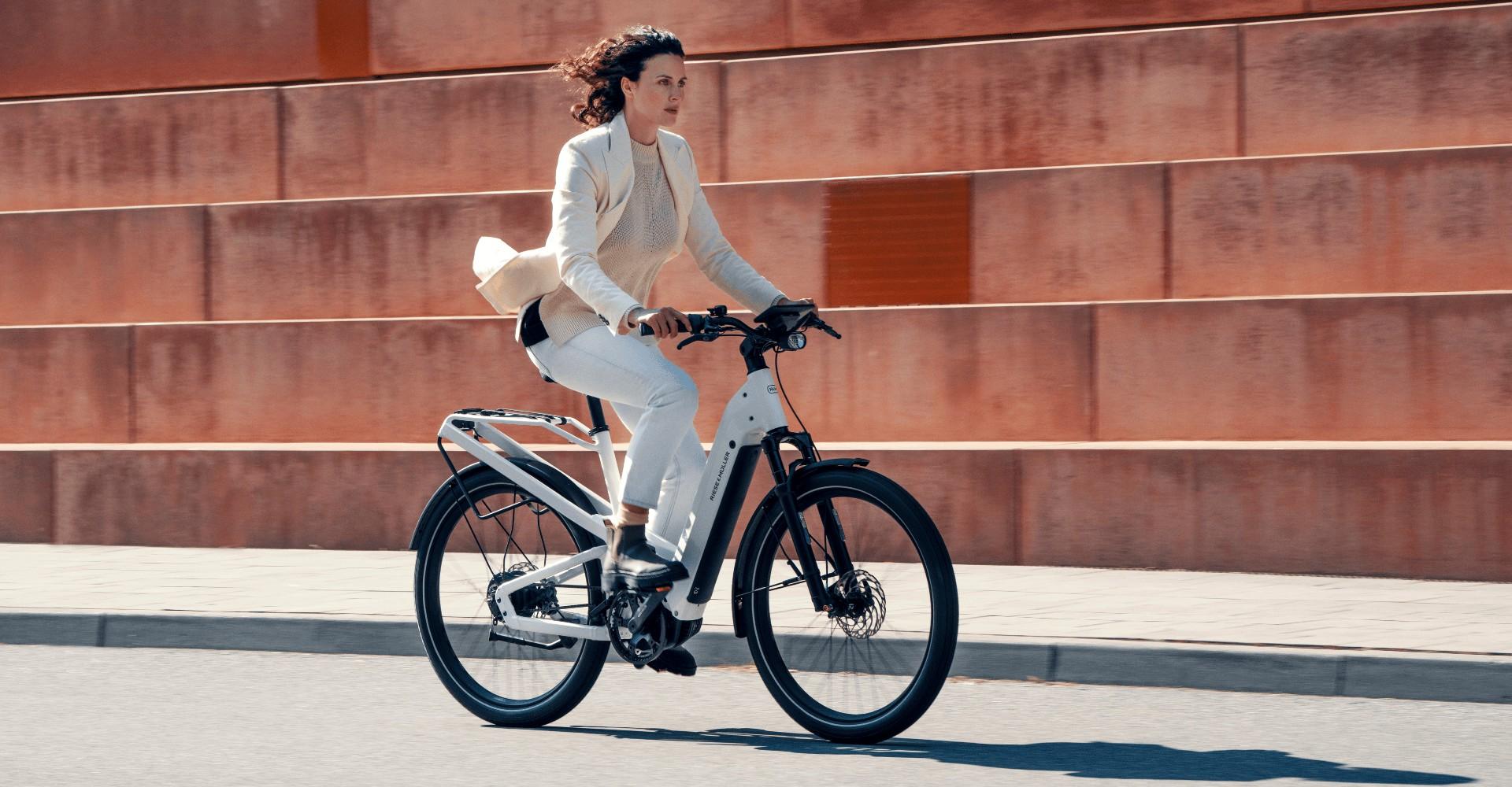 Das Bild zeigt eine Frau, die auf einem Riese & Müller Homage e-Bike fährt. Das Fahrrad besticht durch sein moderne