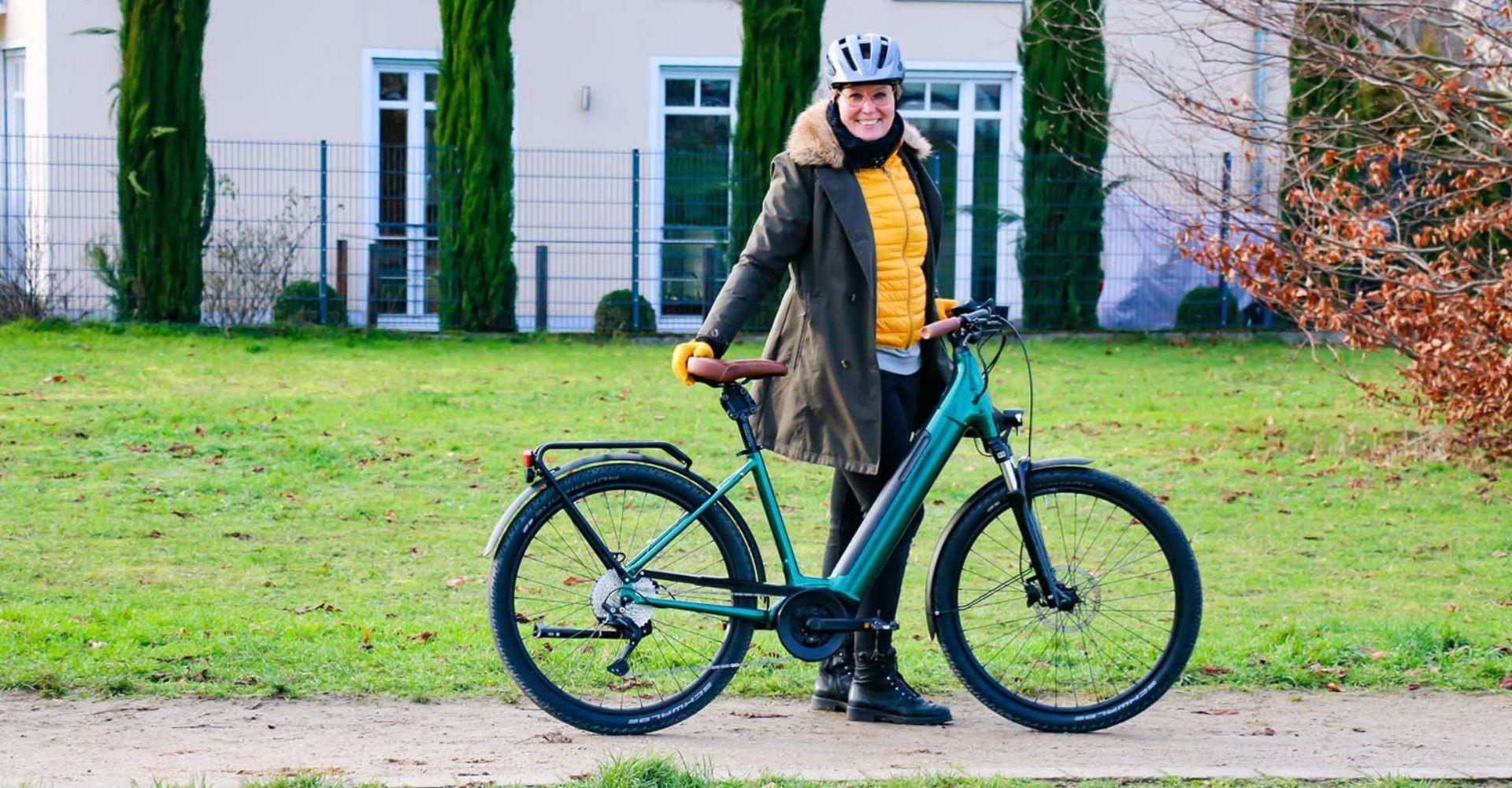 Sandra steht vor dem Cannondale Adventure Neo 1 EQ auf einer Wiese