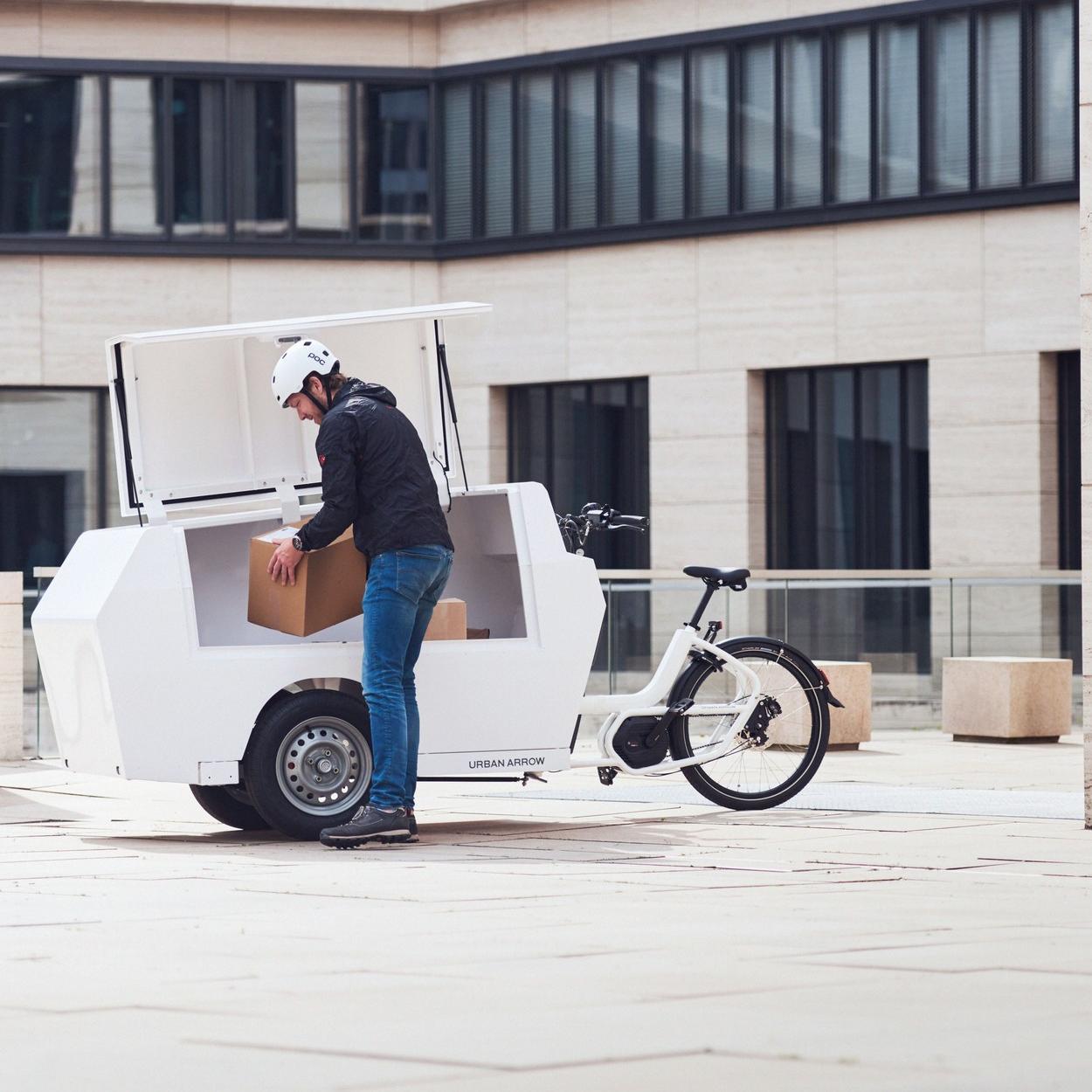 Eine Person hebt ein Paket aus dem Urban Arrow Tender Lastenrad