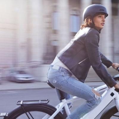 Frau auf weißem Speed-Pedelec in der Stadt mit Helm
