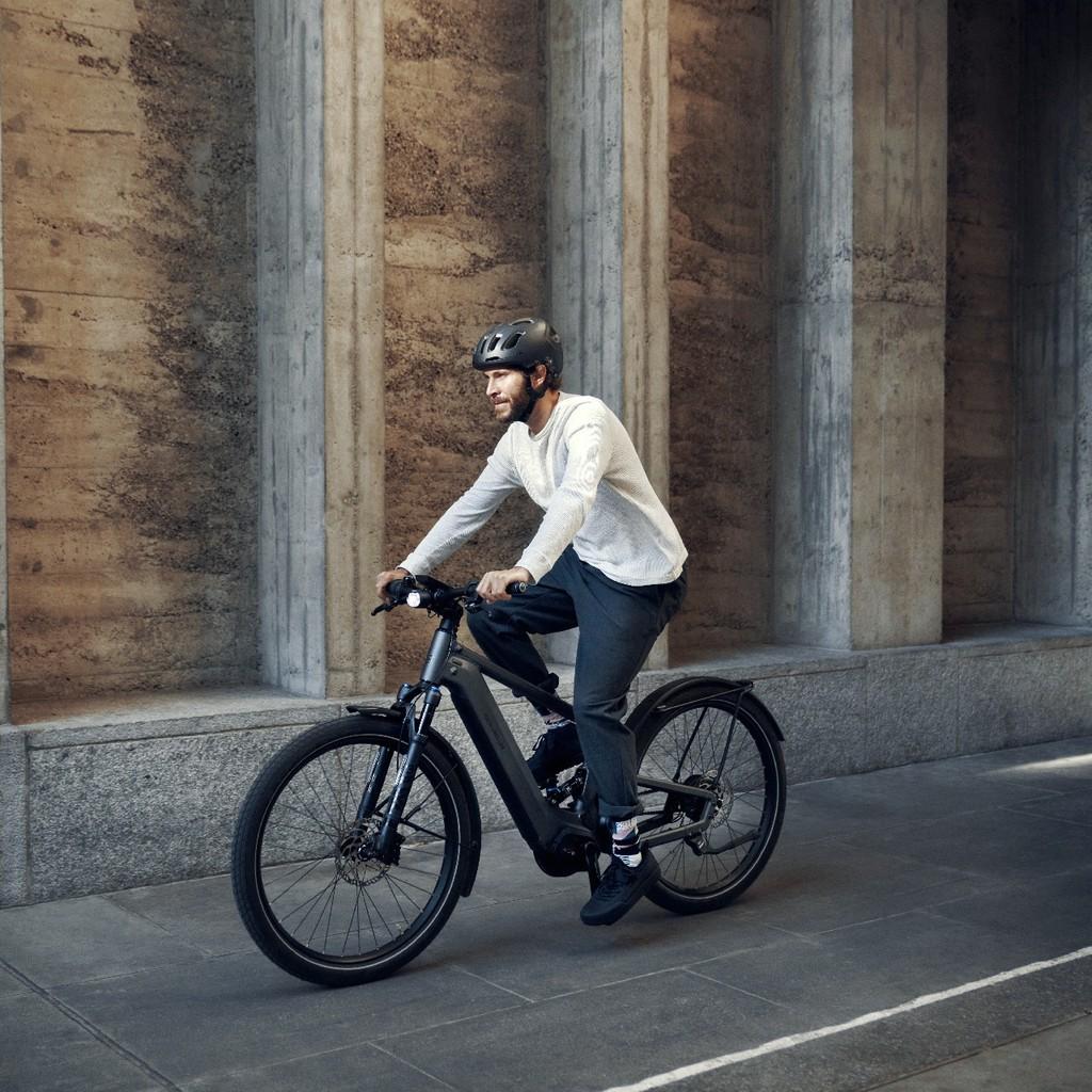 Mann fährt mit Riese und Müller Delite e-Bike an einer grauen Wand entlang