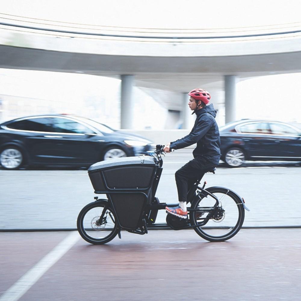 Im Rahmen der Lastenrad Förderung in Frankfurt fährt ein Mann mit einem Lastenrad gerade durch die Stadt.