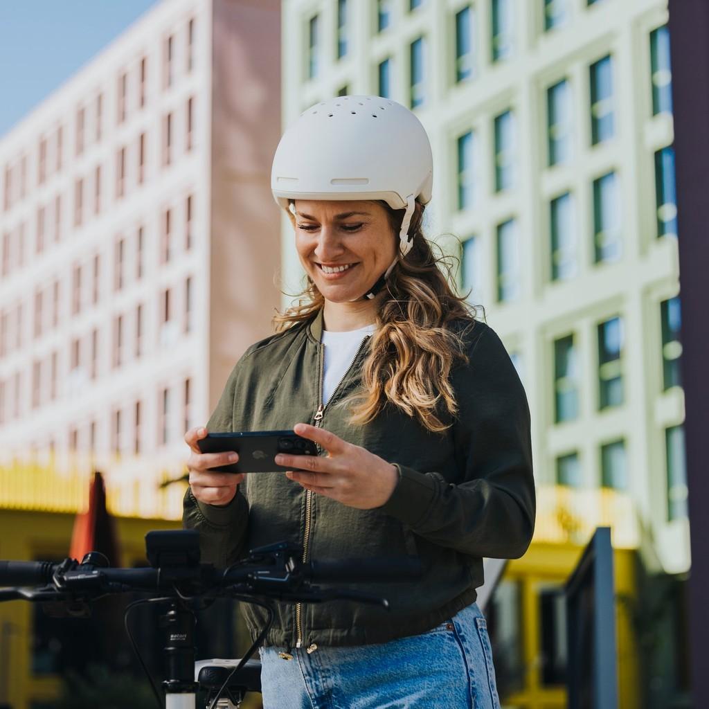 Frau steht mit dem Bosch e-Bike Computer neben ihrem City e-Bike in der Stadt.